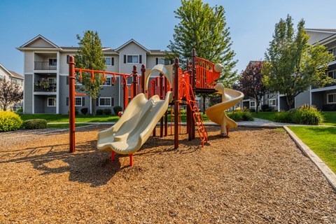 A playground with a yellow slide and red structure.