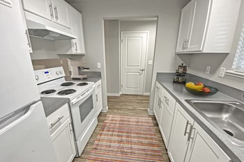 Kitchen Double galley kitchen, wood-like floors, full-size fridge, top and bottom cabinets, oven, stovetop, and sink. - Photo Gallery 3