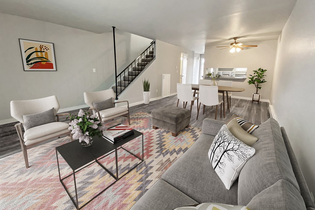 Bright open living room with carpeted stairs to the left and dining area on the right. Wood-style floors and ceiling fan.at Quilceda Gardens, Marysville, Washington