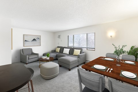 A modern living room with grey furniture and a wooden dining table at Rock Creek Apartments in Billings, MT.