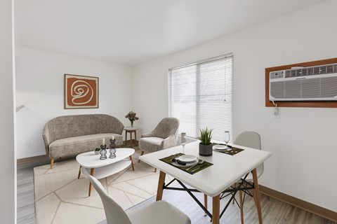 A dining room with a white table and chairs that opens to a living room at our Billings Apartments in Montana.