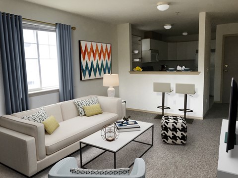 a living room with a white couch and a coffee table, large window and bar looking into a kitchen area at Sky Vue, Bellingham, WA