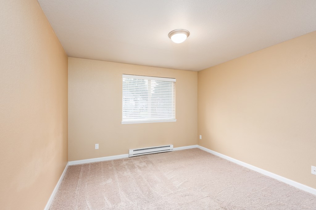 an empty room with beige walls and a window