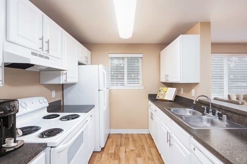 a kitchen with white appliances and counters and a sink