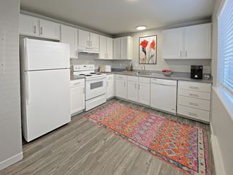 L-shaped kitchen with top and bottom cabinet storage, gray countertops, white appliances, and a large window on the right wall.at Quilceda Gardens, Washington