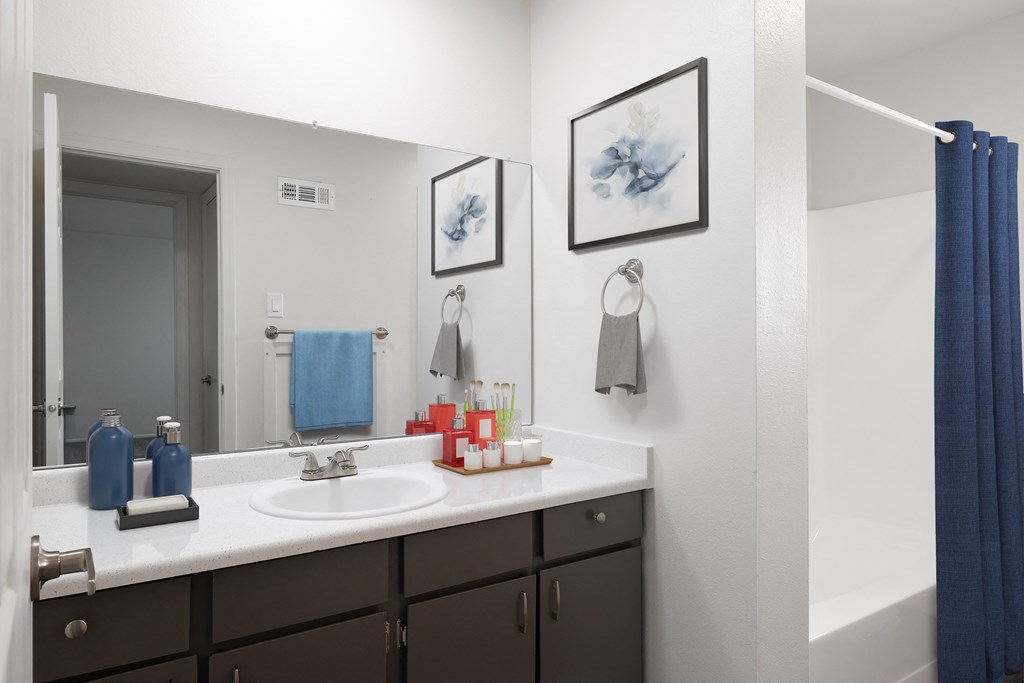 a bathroom with a sink and a mirror and a blue shower curtain