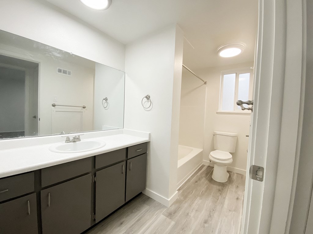 Spacious full bathroom with counter space, ample cabinet storage, sink, towel racks, shower, toilet, and frosted glass window.at Summit, Pocatello, ID