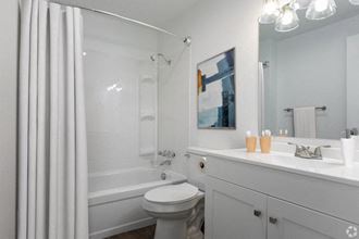 a full bathroom with a white vanity sink, under-sink cabinets, a large mirror, and toilet. Staged with a shower curtain, art and soap. at Talavera, Boise, 83705 - Photo Gallery 5