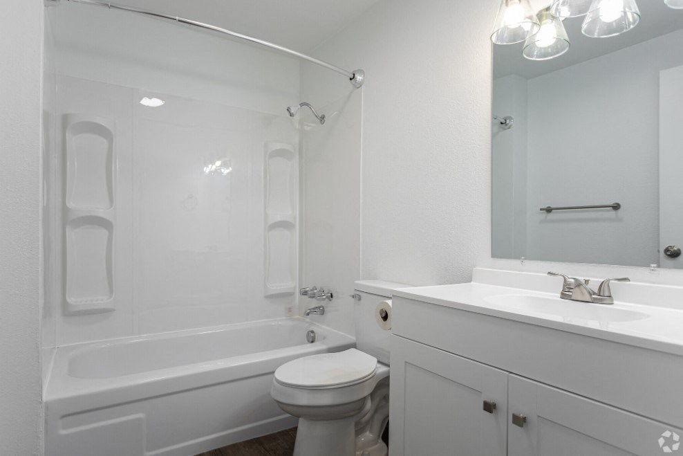 Full bathroom with faux wood flooring, a white vanity sink with under cabinet storage, mirror, toilet, and shower. at Talavera, Boise, Idaho