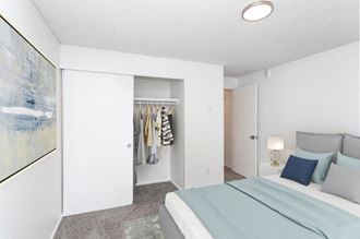 A bedroom with white walls, double sliding doors to large closet and gray carpets. Staged with a queen-size bed, a rug, side tables and a lamp. at Talavera, Boise, 83705