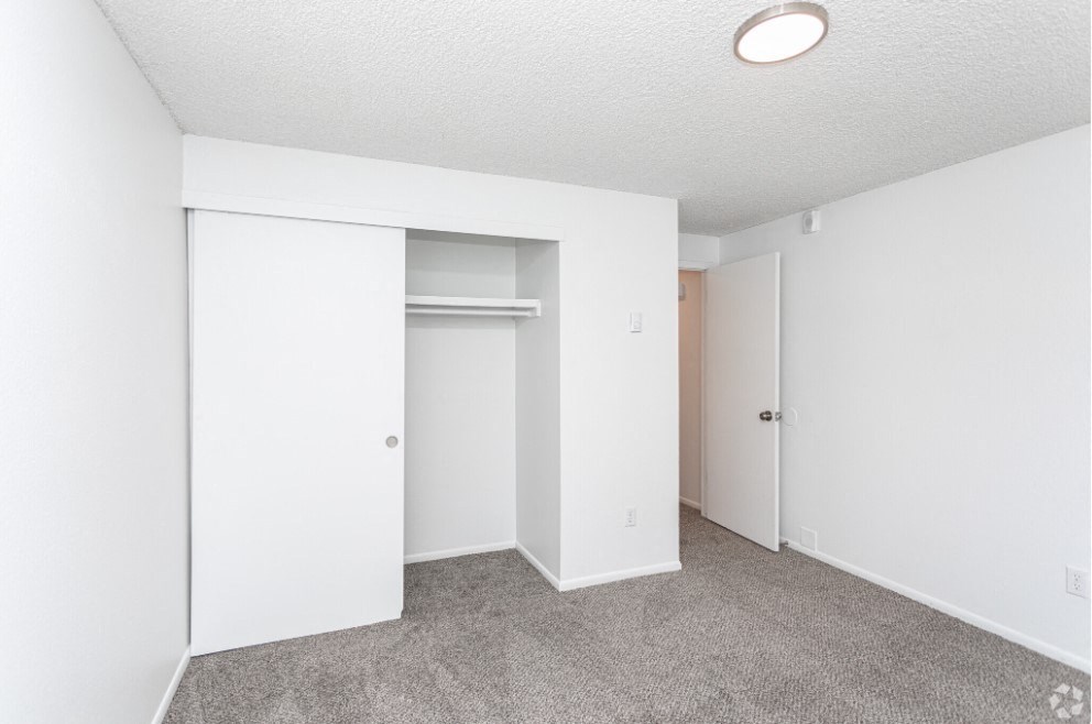 Carpeted bedroom with white walls, looking at the large closet with double sliding doors and shelf storage. at Talavera, Boise, 83705