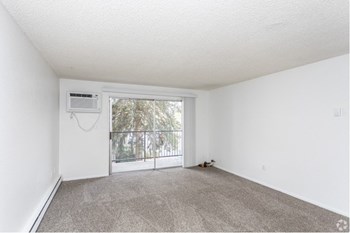 Spacious living room with carpeted floors, AC unit, and oversized sliding glass doors to a private balcony. - Photo Gallery 11