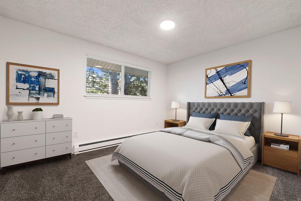 furnished bedroom with white walls and carpeting and a bed