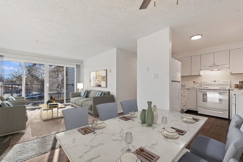 a living room with a table and chairs and a kitchen with a sliding glass door