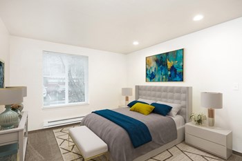 Bedroom with a large window on the far wall. Staged with a queen-size bed, two side tables, lamps, a rug, and a bench. - Photo Gallery 10