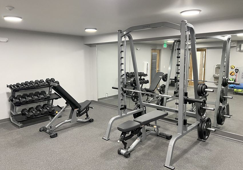 University Glen Fitness Center Fitness center with weight rack, free weights, squat, bench press rack, and two benches.