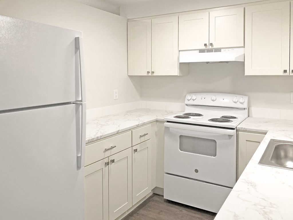 Updated kitchen with white top and bottom cabinets, full-size fridge, oven, stovetop, rangehood, sink, and dishwasher. at Talavera, Boise, 83705