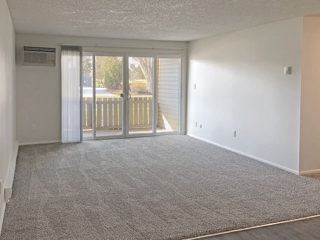 Spacious living room with gray carpet and large sliding glass doors to private patio in Boise, ID at Talavera.