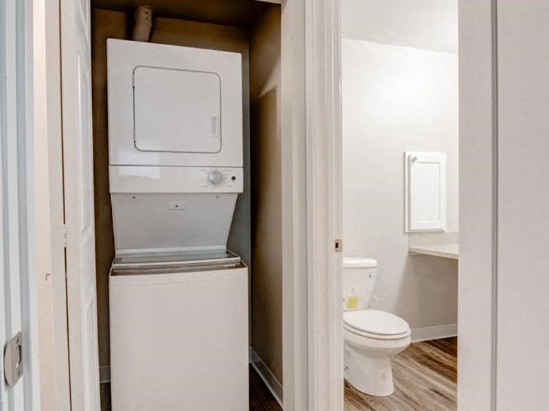 A laundry closet with a white stacked washer and dryer and a door to the bathroom on the right. at Pointe East, Washington, 98424