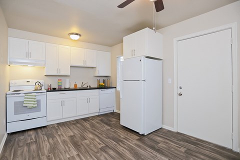 an empty kitchen with white cabinets and a white refrigerator