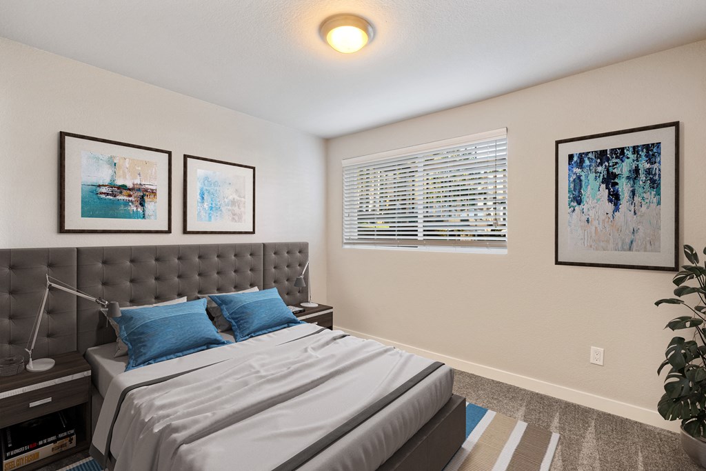 Bedroom with large window, staged bed, carpet, side tables and art above bed.at Capitol Crossing, Olympia