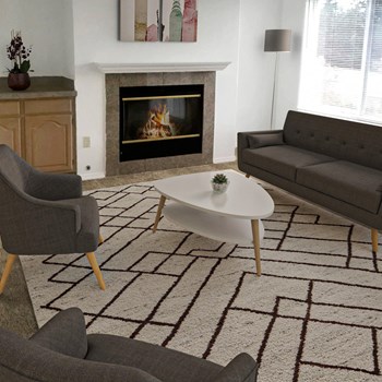 Living Room Living room with a fireplace in the center and a large window behind the staged couch. Wood cabinets sit to the left of the fireplace. - Photo Gallery 2