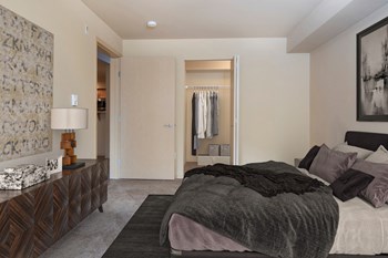 Bedroom Carpeted bedroom with a queen size bed, a long set of drawers, art on the walls, and a closet with an accordion door - Photo Gallery 6