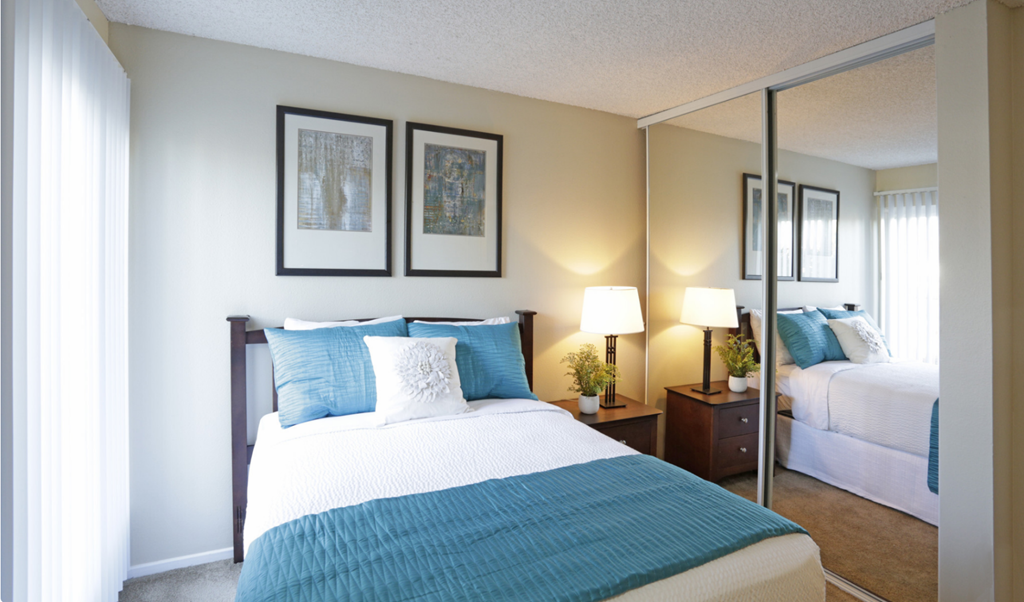 Bedroom with mirrored closet doors, full size bed and night stand  at Pacific Sands, San Diego, California