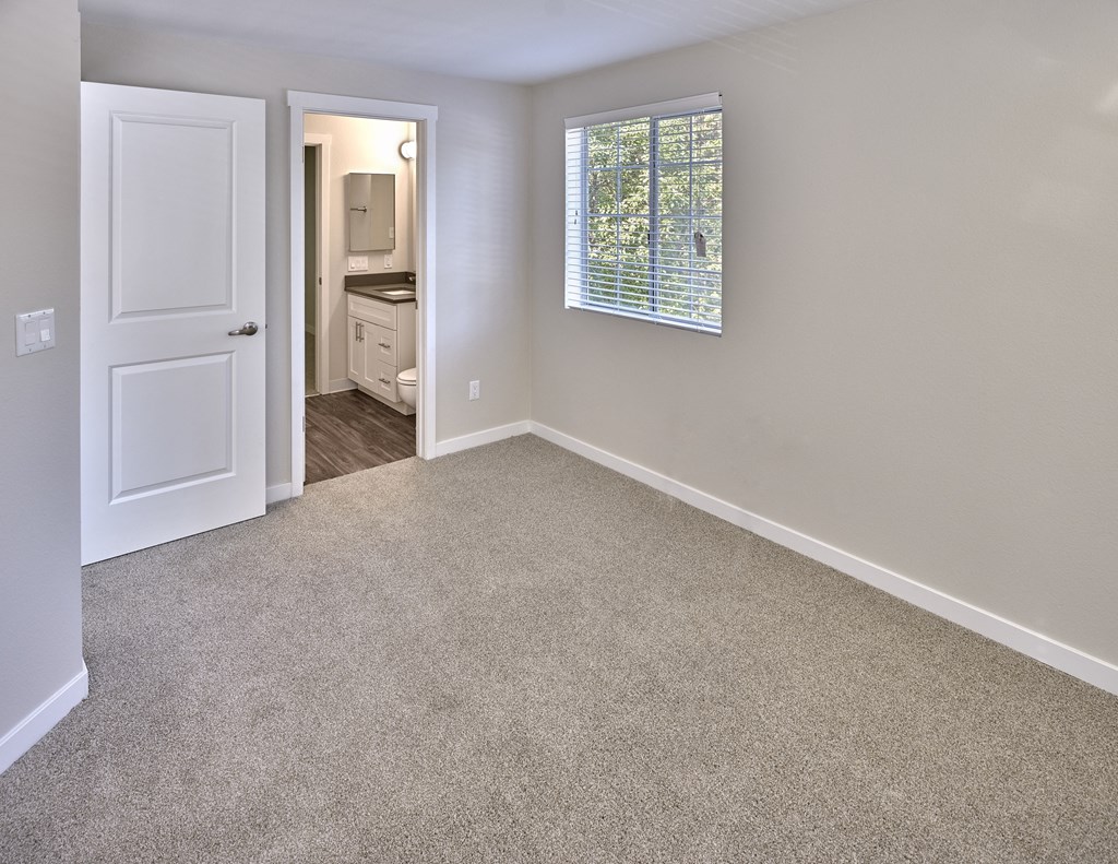 an empty room with carpet and a door to a bathroom