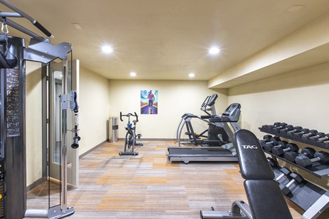 Indoor gym with treadmill, elliptical, stationary bike, cable station, free weights, and a bench.at Cedarwood, Washington, 98801