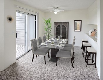 Dining area with table and chairs in the center, a ceiling fan with light, sliding glass doors to the left, and a breakfast bar on the right. - Photo Gallery 2