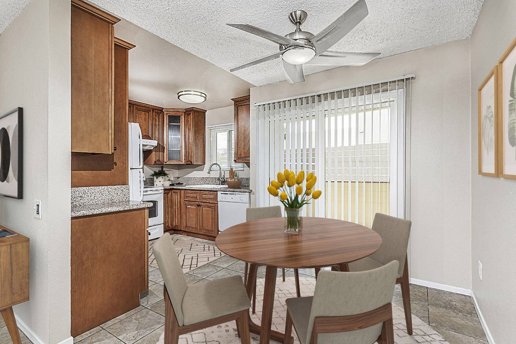 Apartment dining area with a table and four chairs looking out to the private patio. The kitchen is off to the left at Pacific Sands, California, 92117
