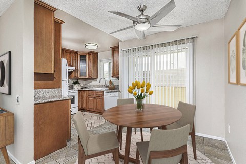 Apartment dining area with a table and four chairs looking out to the private patio. The kitchen is off to the left at Pacific Sands, California, 92117