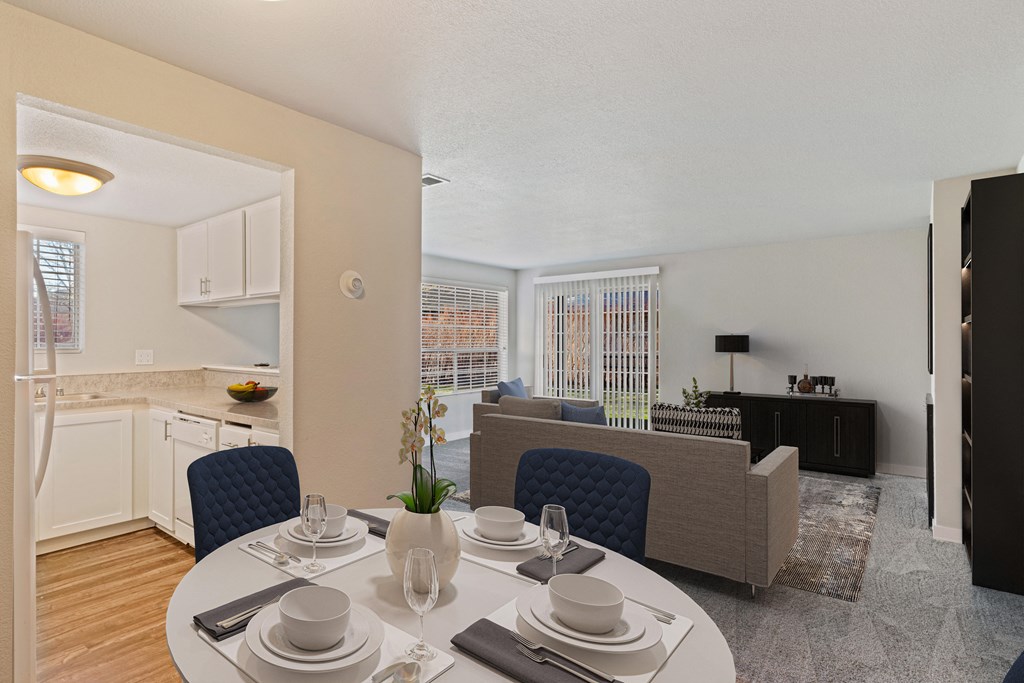 Dining area with view of kitchen leads into carpeted living room, with large window and sliding glass doors.at Capitol Crossing, Olympia, WA