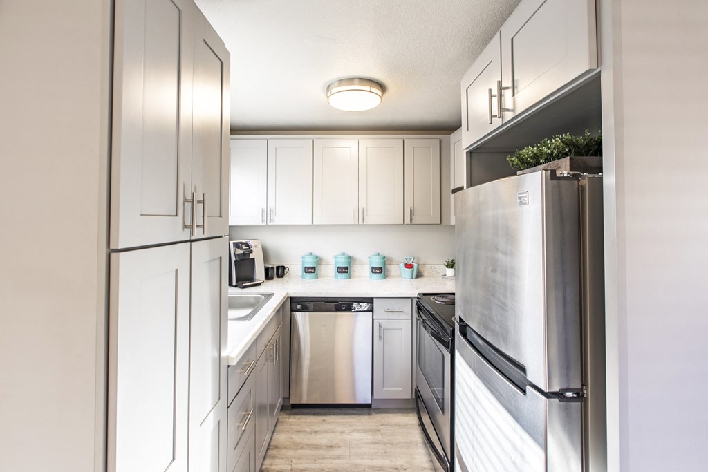 Kitchen in community lounge with stainless steel appliances and new white cabinets at The Lakes Apartments, Moses Lake, WA.
