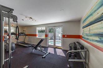 Fitness center with treadmill, elliptical, bench, free weights, cable machine, and double doors accessing the pool. at Quartz Creek, Washington - Photo Gallery 4