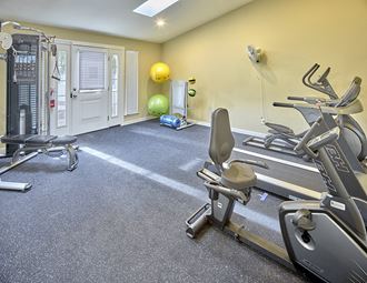 Fitness center with treadmill, elliptical, weight machine, exercise balls, and recumbent bike.
