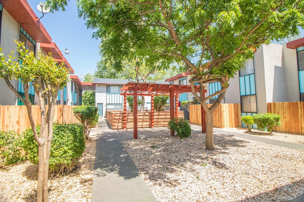 Outdoor courtyard with paved path and landscaping leading to pavilion and dog park.at Woodland Village , Woodland California