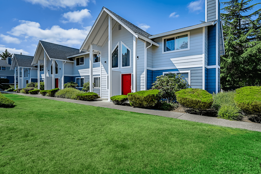 Hawks Prairie Community Exterior Paved path leading to Hawks Prairie Townhomes, exterior blue accents, and bright green well-maintained landscaping. at Hawks Prairie, Washington