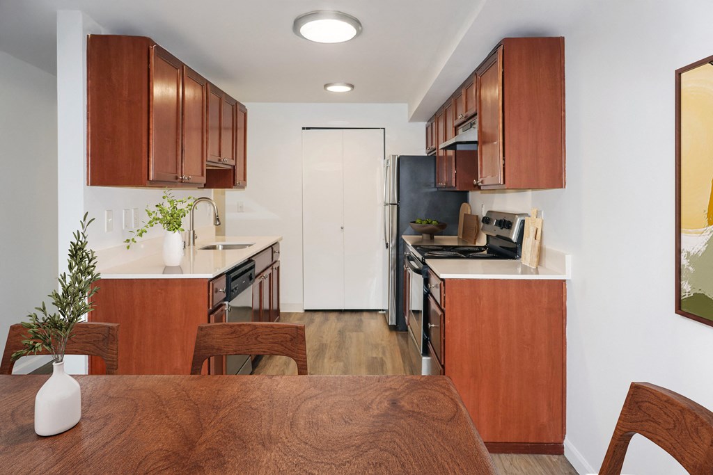 A kitchen with brown wooden cabinets and a white door at Heritage Grove Apartments in Renton, WA