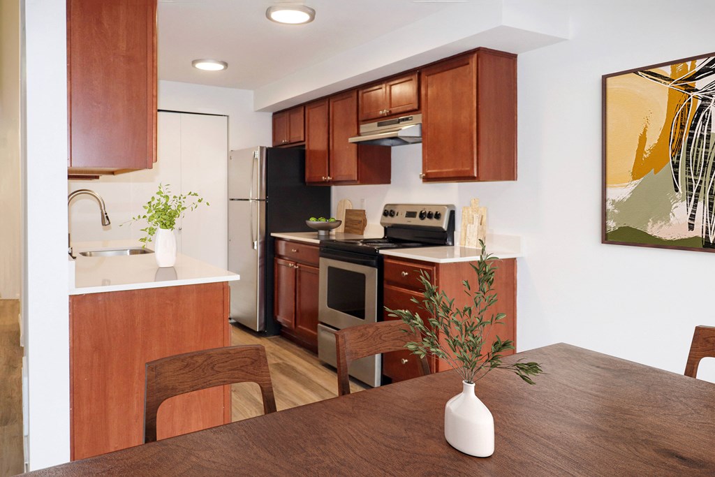 a kitchen with stainless steel appliances and brown wooden cabinets at Heritage Grove Apartments in Renton, WA