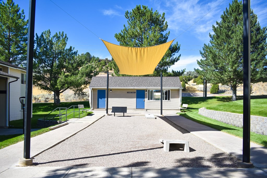 Covered game area at Kirkwood Meadows Apartments in Pocatello, ID. Green grass area with Corn Hole game.