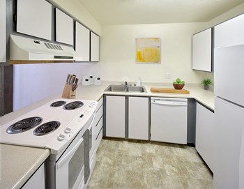 Kitchen Kitchen with upper and lower cabinets, a sink, and white appliances. There is a fridge, dishwasher, and oven with a cooktop. - Photo Gallery 3