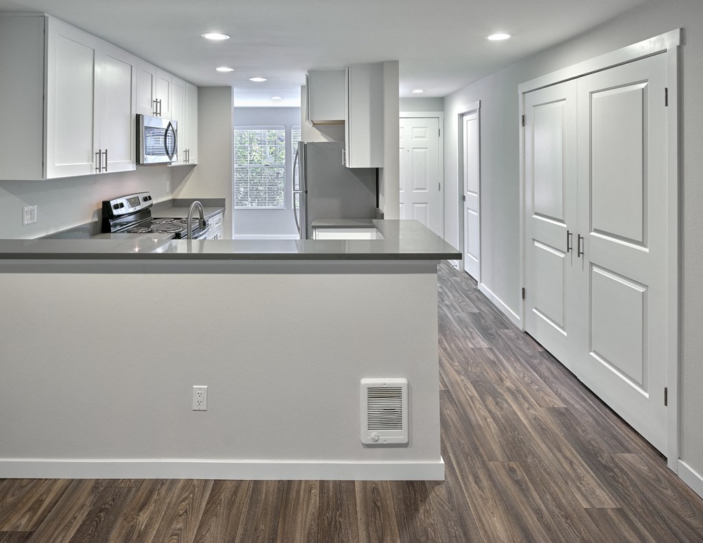 an empty kitchen with white cabinets and a large counter top  at Edmonds Gateway, Edmonds, WA, 98026