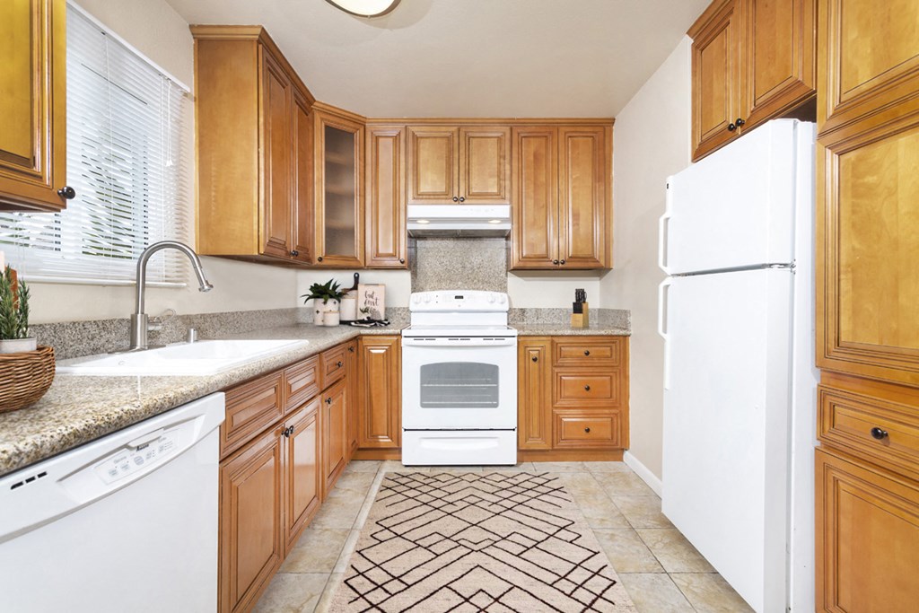 Large U-shaped kitchen with granite countertops, dishwasher, sink, stove, oven and fridge at Pacific Sands, San Diego, California