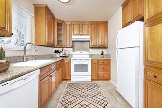 Large U-shaped kitchen with granite countertops, dishwasher, sink, stove, oven and fridge.
