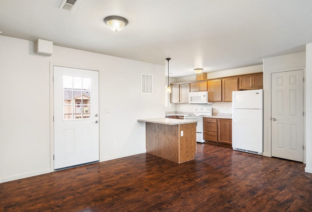 A kitchen with hardwood flooring, a breakfast bar, a microwave, oven, stove top, and full-size fridge. Closet door to the right of the fridge. at Pine Tree Park, Kennewick, 99337