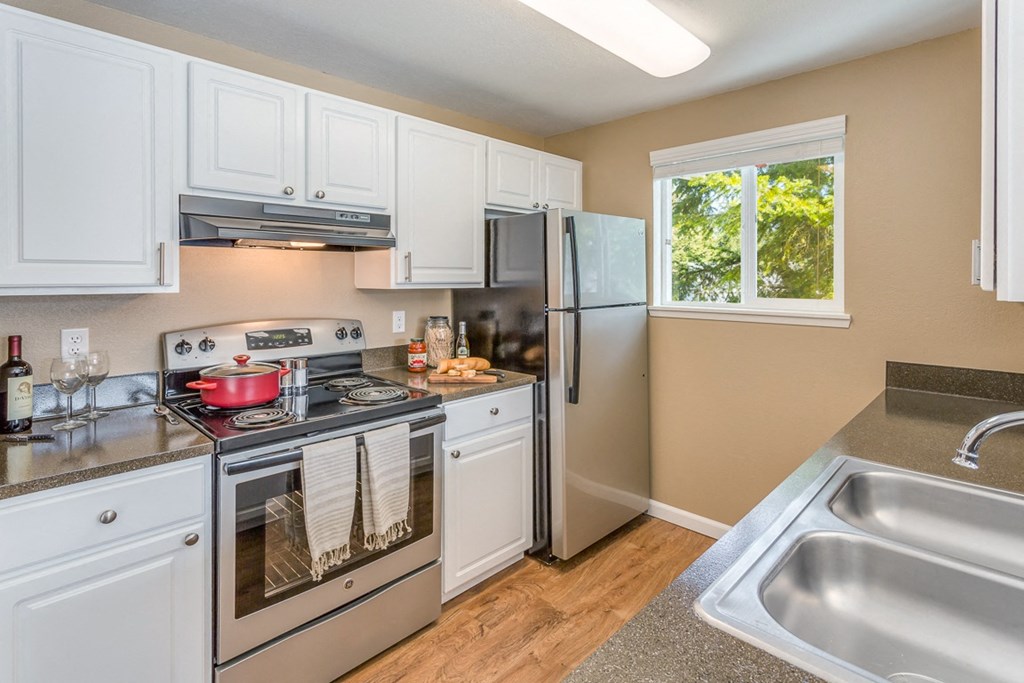 a kitchen with stainless steel appliances and white cabinets  at Springfield, Renton, 98055