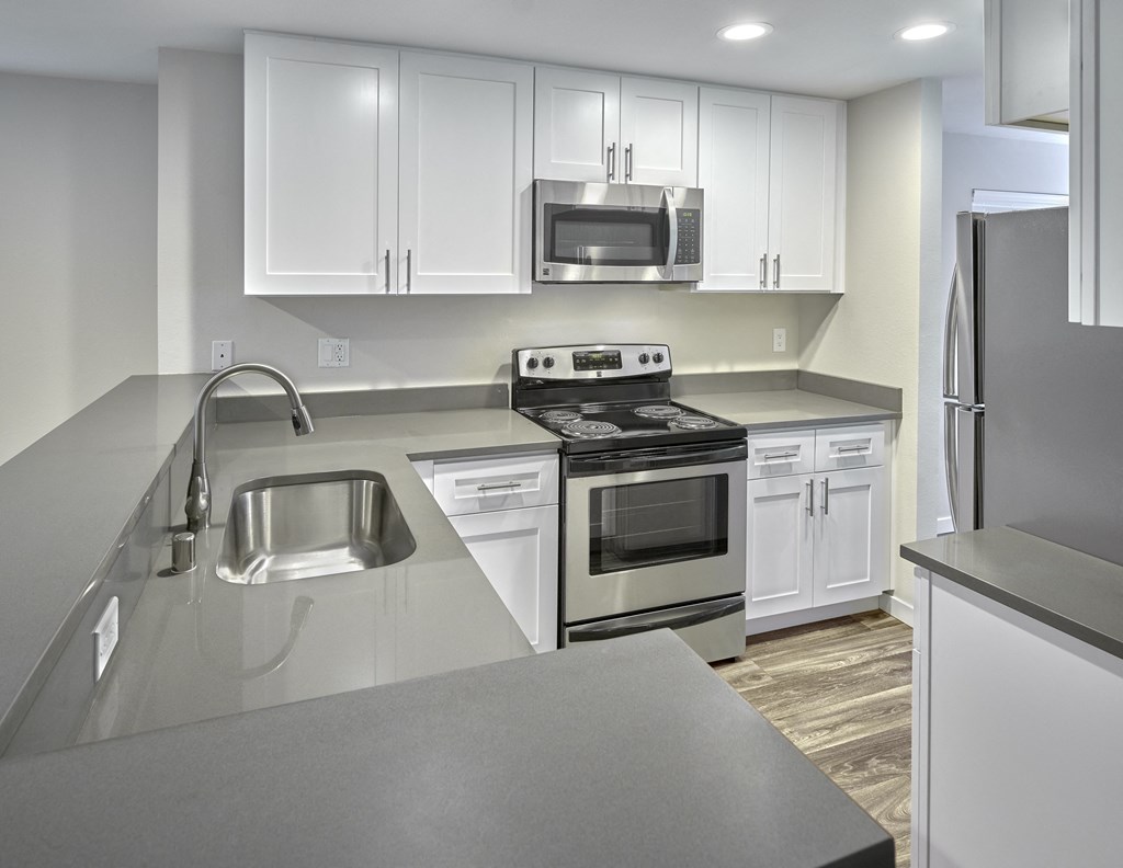 an empty kitchen with white cabinets and stainless steel appliances  at Edmonds Gateway, Washington