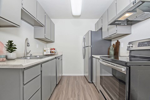 Kitchen with fridge, oven with cooktop, dishwasher, and sink.  Upper and lower cabinets on both sides.